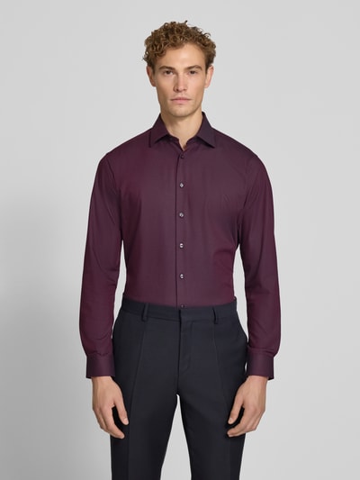 Männermodel trägt Regular Fit Business-Hemd mit Kentkragen von Christian Berg Men, bordeauxfarben, Baumwoll-Mix mit Stretch, Ganzkörperansicht von vorne.
