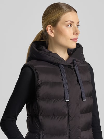 Vrouwenmodel draagt Regular Fit bodywarmer in stiksels van FUCHS SCHMITT, zwart, capuchon met tunnelkoord, steekzakken met ritssluiting, ruglengte maat 36: 77 cm, schouderbreedte: 41 cm, borstwijdte: 51 cm, detailopname bovenlichaam