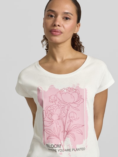 Frauenmodel trägt Regular Fit T-Shirt aus Viskose-Mix mit floraler Print von Christian Berg Woman, Rundhalsausschnitt, cremeweiß mit rosa Floraler-Print, Rückenlänge bei Größe S 55 cm, Ganzkörperansicht von vorne.