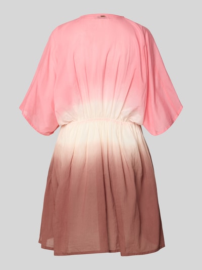 Frauenmodel trägt Strandkleid mit V-Ausschnitt Modell 'Mundoly' von Barts, Reine Baumwolle, Taillierter Schnitt, Minikleid, Rückseitiges Label-Detail, Farbverlauf Rosa zu Beige, fließender Stoff, Ganzkörperansicht Rückansicht.