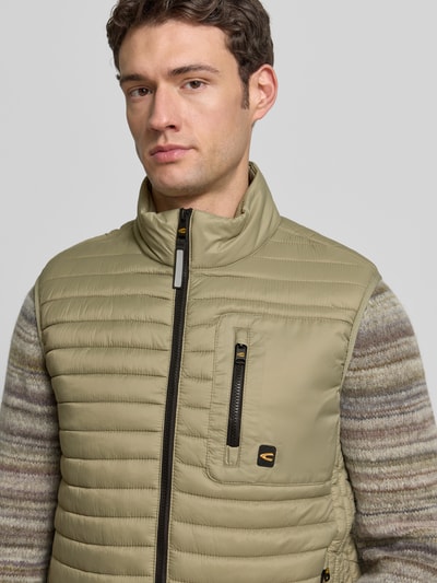 Männermodel draagt Steppweste mit Stehkragen van camel active in regular fit met borstzak met ritssluiting, labeldetail en steekzakken, nahaufnahme bovenlichaam. Ruglengte maat M: 68 cm, schouderbreedte: 46 cm, borstwijdte: 60 cm.