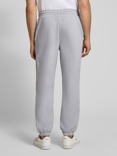 Männermodel trägt graue Regular Fit Sweathose aus Baumwoll-Mix von Lacoste, lockere Passform, Herren Sweathose, Ganzkörperansicht Rückansicht.