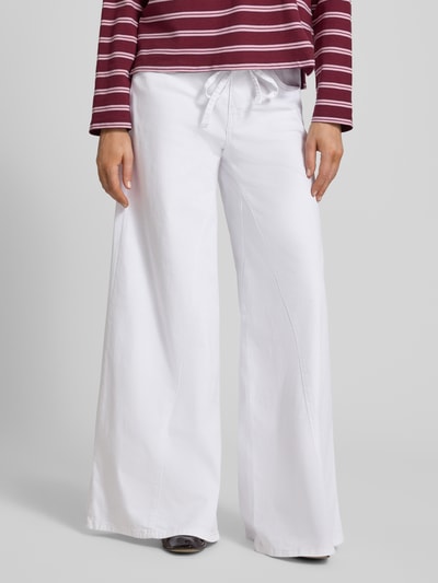 Modelka nosi Wide Fit Jeans mit Zierschleife od MAC, biały kolor, elastyczna bawełna, 5 kieszeni, szerokie nogawki, szerokość w rozmiarze 36/32: 38 cm, długość nogawki od wewnątrz w rozmiarze 36/32: 82 cm, widok z przodu, zdjęcie całej sylwetki.