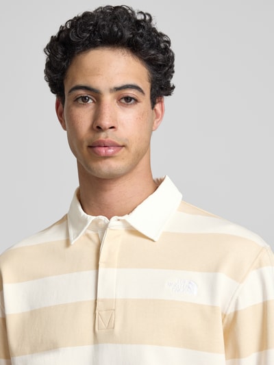Männermodel trägt Sweatshirt mit Polokragen und Label-Stitching von The North Face in Creme-Beige mit Streifen, Reine Baumwolle, Regular-Fit, Nahaufnahme Oberkörper.