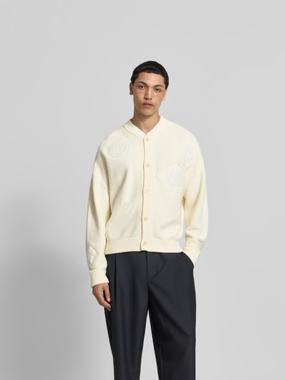 Männermodel trägt Strickjacke mit floralem Stitching von MAISON KITSUNÉ, Baumwoll-Mix, Regular-Fit, elfenbeinfarben, Ganzkörperansicht von vorne.