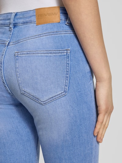 Vrouwenmodel draagt Skinny Jeans mit mittelhohem Bund in hellblauer Waschung van REVIEW, Mix van katoen en elastaan, skinny fit, 5-pocketmodel, lichtblauwe kleur, knoop- en ritssluiting, detailopname achterkant.