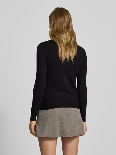 Frauenmodel trägt Slim Fit Strickjacke aus Viskose-Mix Modell 'NORA' von Pieces, unifarben schwarz, gerippte Abschlüsse, Ganzkörperansicht Rückansicht.