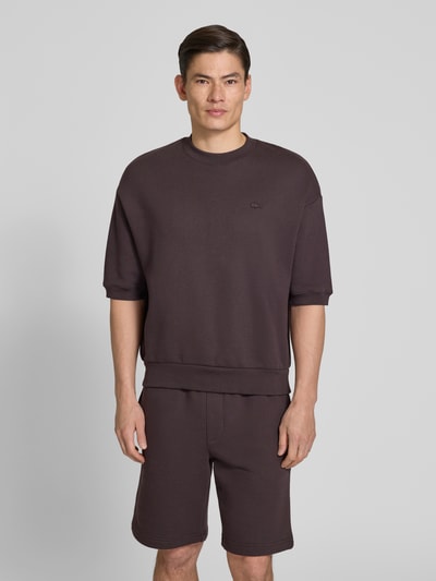 Mężczyzna nosi Relaxed Fit Sweatshirt aus reiner Baumwolle von Lacoste, efekt: jednolity kolor, krój relaxed fit, wyhaftowane logo, okrągły dekolt, długi rękaw, prążkowane zakończenia, dzianina dresowa, bawełna, Ganzkörperansicht von vorne.