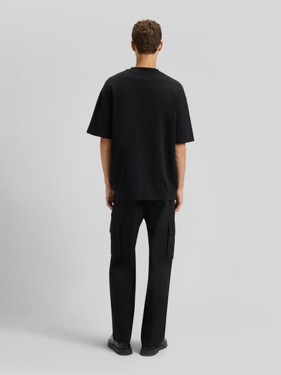 Männermodel trägt Oversized T-Shirt aus reiner Baumwolle Modell 'DINKEE' von HUGO in Schwarz, unifarben, kurze Ärmel, Ganzkörperansicht Rückansicht.