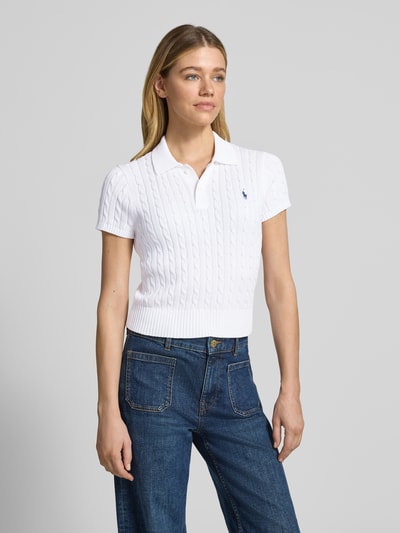Frauenmodel trägt Regular Fit Strick-Poloshirt aus reiner Baumwolle von Polo Ralph Lauren in Weiß mit Zopfmuster und Label Stitching, unifarben, Polokragen, Kurzarm, gerippte Abschlüsse, Stricktextur, Ganzkörperansicht von vorne.