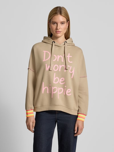 Frauenmodel trägt Oversized Hoodie mit Statement-Print von miss goodlife in Beige mit pinkem Schriftzug, reine Baumwolle, Ganzkörperansicht von vorne.