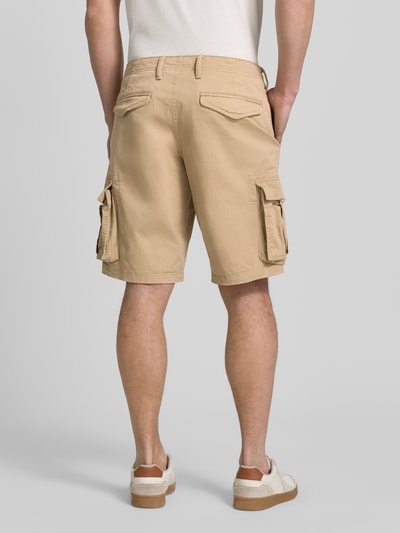 Männermodel trägt Shorts mit Cargotaschen Modell 'NEW 24' von GAP, Baumwoll-Elasthan-Mix, Regular-Fit, beige, Ganzkörperansicht Rückansicht.