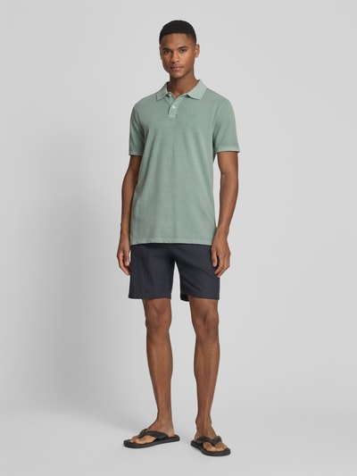 Männermodel trägt Slim Fit Poloshirt mit Label-Stitching von GAP, mintgrün, Baumwoll-Elasthan-Mix, Knopfleiste, Ganzkörperansicht von vorne