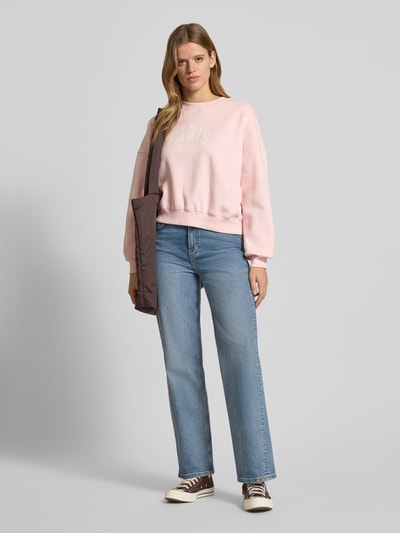 Frauenmodel trägt Sweatshirt mit Label-Print und Rundhalsausschnitt von Review, rosa, Baumwoll-Mix, Relaxed-Fit, Ganzkörperansicht von vorne.