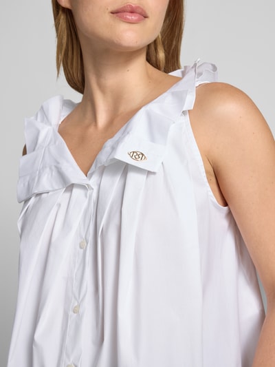Frauenmodel trägt Bluse mit Umlegekragen und Rüschen von Rinascimento, weißer Baumwoll-Mix, Knopfleiste, Label-Detail, Nahaufnahme Oberkörper.