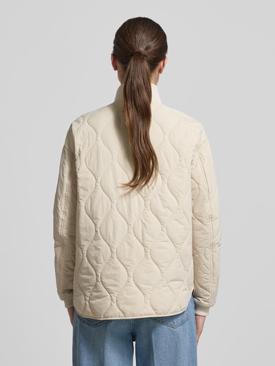 Vrouwenmodel draagt camel active Steppjacke mit Stehkragen in beige, recht pasvorm, elastische mouwboorden, ruglengte 66 cm, schouderbreedte 42 cm, borstwijdte 51 cm, mouwlengte 64 cm, tweewegritssluiting, kinbescherming, ganzekop zicht rugaanzicht.