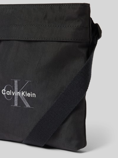 Produktfoto, schwarze Crossbody Bag mit Label-Stitching von CK Calvin Klein, rechteckig, grobe Textilstruktur, Reißverschluss, Detailaufnahme