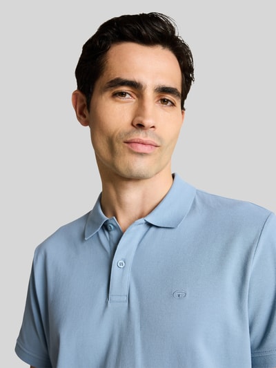 Männermodel trägt Regular Fit Poloshirt aus reiner Baumwolle von Tom Tailor in Optik: Unifarben mit Logo-Stitching, Nahaufnahme Oberkörper.