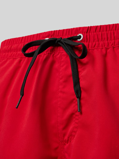 Produktfoto, leuchtend rote Regular Fit Badehose mit schwarzem Kordelzug und Logo-Patch von Quiksilver, Modell 'Everyday', glatte Textur