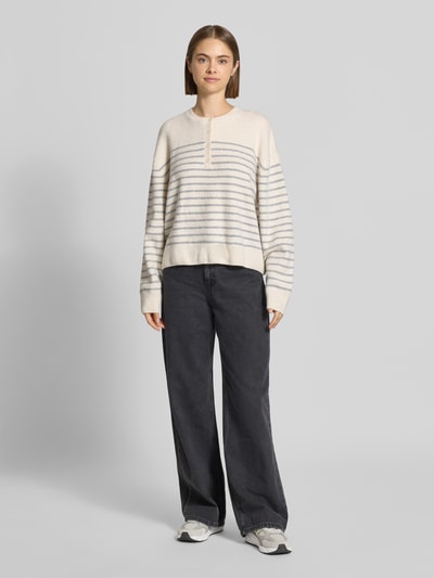 Vrouwenmodel draagt Relaxed Fit Pullover in tricotlook van REVIEW, crème met grijze strepen, Henley-kraag, vooraanzicht, Ganzkörperansicht von vorne.