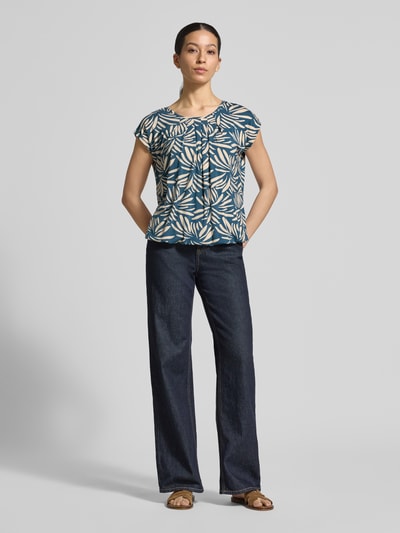 Frauenmodel trägt Regular Fit Bluse aus Viskose-Mix Modell 'Minou' von ZABAIONE mit Floraler-Allover-Print, Kurzärmelig, Rundhalsausschnitt, Elastischer Bund, Rückenlänge 62 cm bei Größe S, Ganzkörperansicht von vorne.