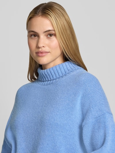 Frauenmodel trägt Relaxed Fit Pullover aus Schurwoll-Mix in Strick-Optik von Lanius in Hellblau mit Rollkragen, Nahaufnahme Oberkörper. Schurwoll-Mix mit Baumwoll-Anteil, Rückenlänge 63 cm, Ärmellänge 50 cm.