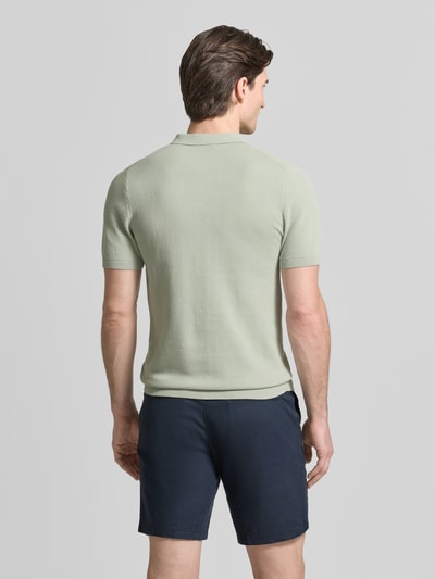 Männermodel trägt Slim Fit Poloshirt in Strick-Optik Modell 'TRITON' von Drykorn, hellgrün, reine Baumwolle, Rückansicht, Ganzkörperansicht.