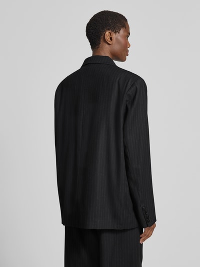 Frauenmodel trägt Relaxed Fit Blazer mit Viskose-Anteil von black palms, Schwarz mit feiner Struktur, Elastischer-Material-Mix, Rückenlänge 76 cm, Ganzkörperansicht Rückansicht.