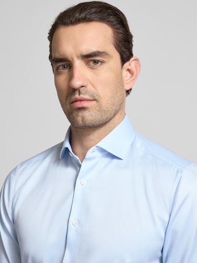 Männermodel trägt Slim Fit Business-Hemd in unifarbenem Design mit Kentkragen von OLYMP Level Five aus reiner Baumwolle, Nahaufnahme Oberkörper.