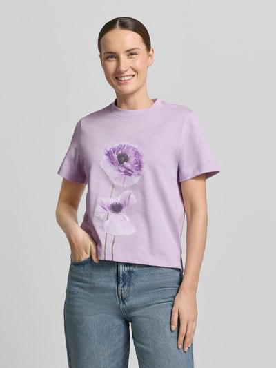 Kobieta modelka nosi T-Shirt z motywem kwiatowym 'FIORE' od Stefanel, bawełna, krój regular fit, liliowy kolor, zdjęcie całej sylwetki z przodu.
