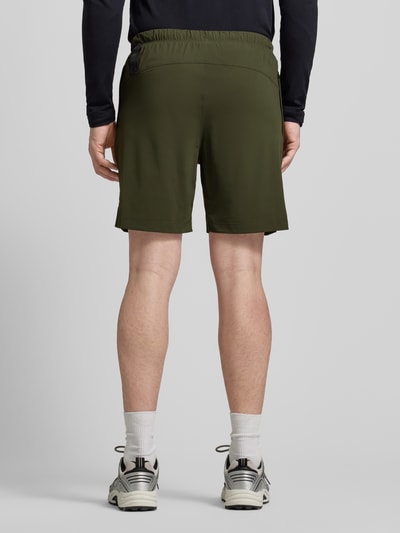 Männermodel trägt Regular Fit Shorts mit Logo-Print von Fabletics in Olivgrün, elastischer Bund, Eingrifftaschen, Ganzkörperansicht Rückansicht.