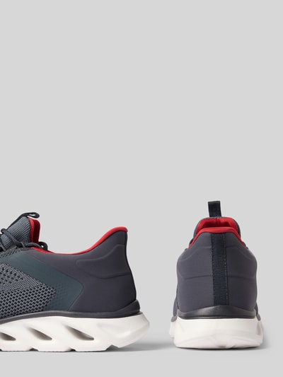 Produktfoto, Sneaker mit Schnürung und Label-Detail Modell 'Caraway' von bugatti in Dunkelblau mit rotem Innenfutter, abgerundete Spitze, weiße Profilsohle, Herren Sneaker, Absatzhöhe 6 cm, Schafthöhe 8 cm, Schaftweite 7 cm, Produkt auf grauem Hintergrund.