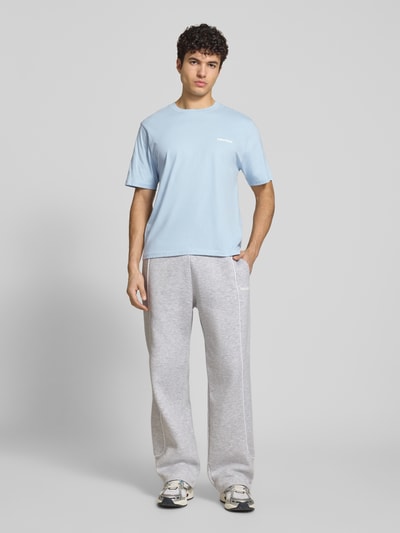 Männermodel trägt T-Shirt mit Logo und Rundhalsausschnitt von REVIEW, Baumwoll-Viskose-Mix, Regular-Fit, Rückenlänge 64 cm, Ganzkörperansicht von vorne.