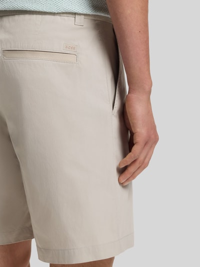 Männermodel trägt Regular Fit Chino-Shorts aus Baumwoll-Mix von BOSS Orange, Optik: Unifarben, Label-Applikation, Ganzkörperansicht Rückansicht.