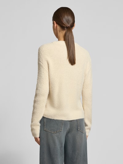 Modelka kobieca ma na sobie Pullover mit weicher Strukturoptik von VERO MODA, kremowy, strukturalny dzianinowy wzór, okrągły dekolt, długie rękawy, ściągacz na dole, widok całej sylwetki z tyłu.