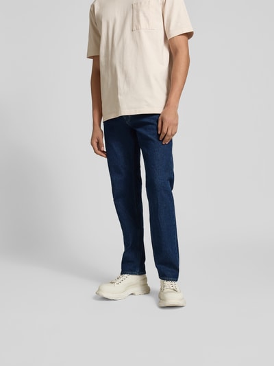 Männermodel trägt Straight Fit Jeans mit Logo-Patch von Closed in Dunkelblau, Baumwoll-Mix, 5-Pocket-Design; Nahaufnahme Oberkörper bis Schuhe.
