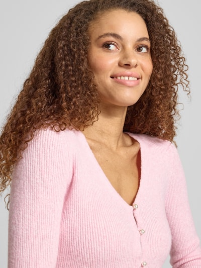Frauenmodel trägt Regular Fit Strickjacke mit Perl-Optik-Knöpfen Modell 'RICA LIFE' von ONLY, Optik: Unifarben, V-Ausschnitt, Rippstrick, Nahaufnahme Oberkörper.