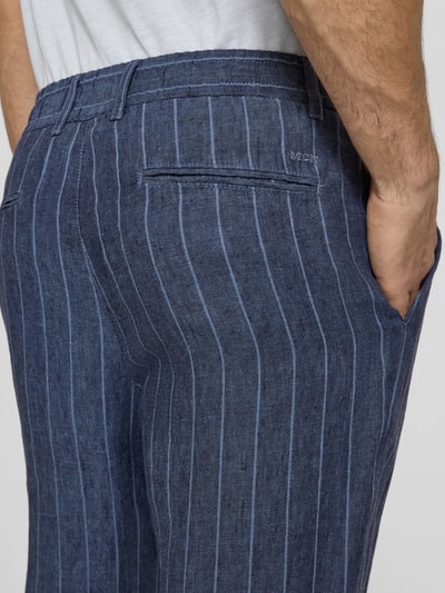 Männermodel trägt Leinenhose mit französischen Eingrifftaschen von MCNEAL in Blau mit feinen Streifen, Reines Leinen, Detailaufnahme Rückansicht.