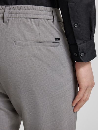 Männermodel trägt Loose Fit Hose mit Gesäßtaschen von bugatti, grauer Baumwoll-Woll-Mix, elastischer Bund, Detailaufnahme Gesäßbereich.