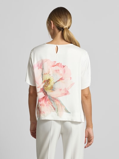 Männermodel trägt Relaxed Fit T-Shirt aus reiner Viskose mit floralem Print von Betty Barclay, biały materiał, duży pastelowy kwiat, okrągły dekolt, elastyczny dół, długość pleców 57 cm, długość rękawa 24 cm, widok całej sylwetki z tyłu