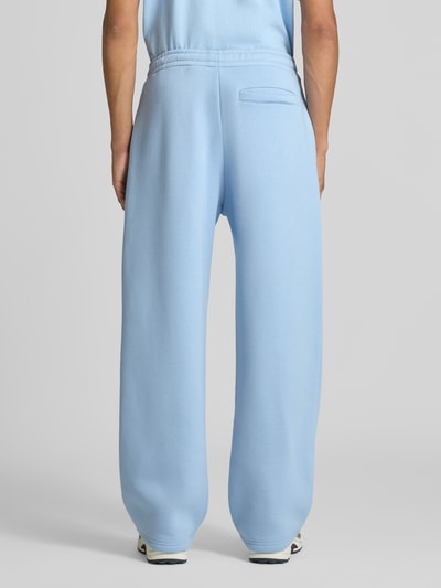 Männermodel trägt Straight Fit Sweatpants Baumwoll-Mix von REVIEW in Hellblau, Gesäßtasche, elastischer Bund, Ganzkörperansicht Rückansicht.