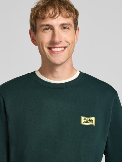 Männermodel trägt Sweatshirt mit Label-Print Modell 'RUSH' von JACK & JONES aus katoenmix, los model, ronde hals, ribboorden, Nahaufnahme Oberkörper.