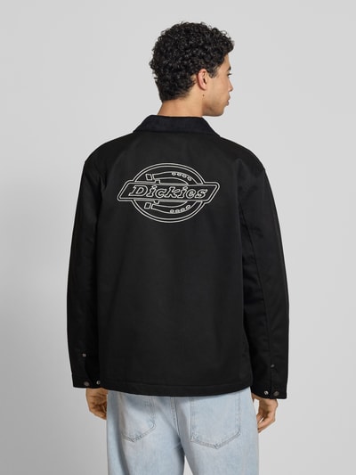 Männermodel trägt Jacke mit Umlegekragen und Label-Detail von Dickies in Schwarz, Material-Mix, Regular-Fit, Rückenlänge 75 cm, Ganzkörperansicht Rückansicht