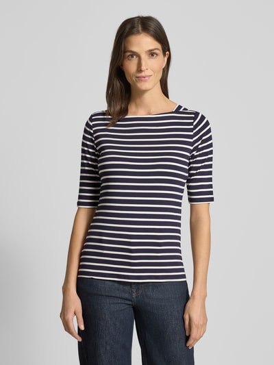 Frauenmodel trägt T-Shirt mit U-Boot-Ausschnitt von Comma im Streifenmuster, Viskose-Mix mit Elasthan-Anteil, Körpernaher Schnitt, 1/2 Arm, Rückenlänge 58 cm in Größe 36, dunkle und helle Farbtöne, Ganzkörperansicht von vorne.