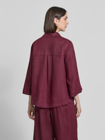 Frauenmodel trägt Relaxed Fit Leinenbluse mit 3/4-Arm von Christian Berg Woman in Weinrot, reine Leinenstruktur, lockere Passform, Hemdblusenkragen, Knopfleiste, Rückenlänge 65 cm, Ärmellänge 48 cm, Ganzkörperansicht Rückansicht.