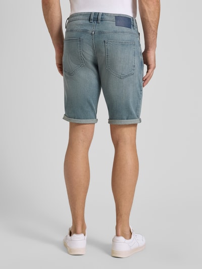 Mężczyzna nosi Regular Fit Jeans Bermudas aus Baumwoll-Mix von Tom Tailor, denim, krój regular fit, gładka tekstura, naszywka z logo, 5 kieszeni, szlufki na pasek, zapięcie na guzik i ukryty zamek, bawełniany miks, widok całej sylwetki od tyłu.