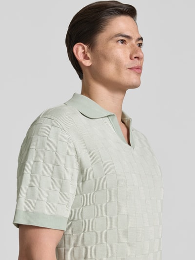 Männermodel trägt Relaxed Fit Poloshirt aus reiner Baumwolle Modell 'MILAS' von SELECTED HOMME, Gitterkaro, Strick, mehrfarbig, Nahaufnahme Oberkörper.