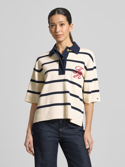 Vrouwenmodel draagt Regular Fit poloshirt uit katoenmix van Tommy Hilfiger met all-over motief, gestikt logo, polokraag, fijngebreid materiaal, geribde mouwboorden en geschulpte rompzoom, voorkant hele lichaam.