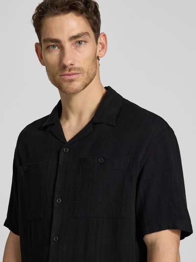 Männermodel trägt Loose Fit vrijetijdsoverhemd uit mix van linnen en viscose van Tom Tailor Denim, look: effen, reverskraag, enkele knopenrij, korte mouw, borstzak, logo-applicatie, nahaufnahme oberkörper.