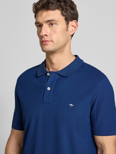 Männermodel trägt Regular Fit Poloshirt mit Label-Stitching von Fynch-Hatton in Blau, reine Baumwolle, kurze Knopfleiste, Nahaufnahme Oberkörper.
